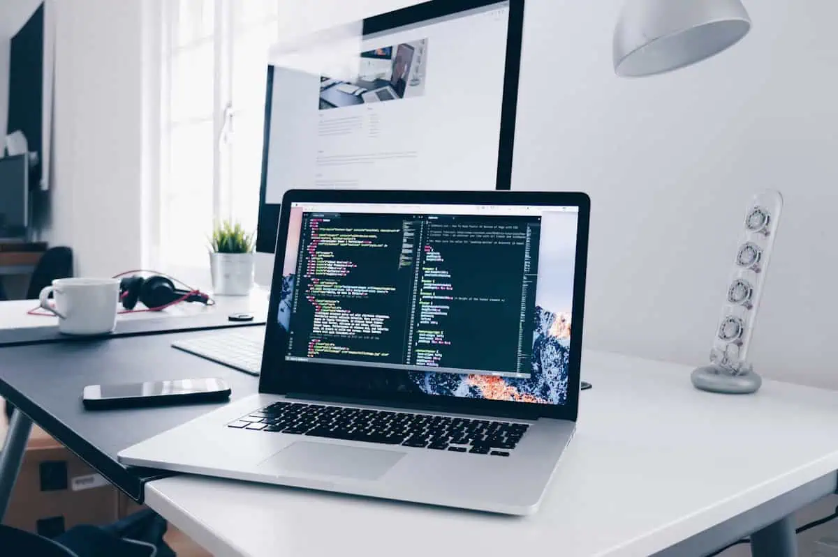 WordPress theme code on a laptop with responsive device testing on a desk